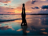woman doing a handstand against a sunset